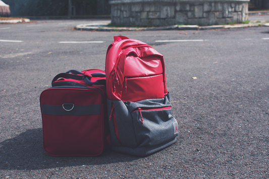 Red and gray backpack and duffel bag side by side comparing travel bag options