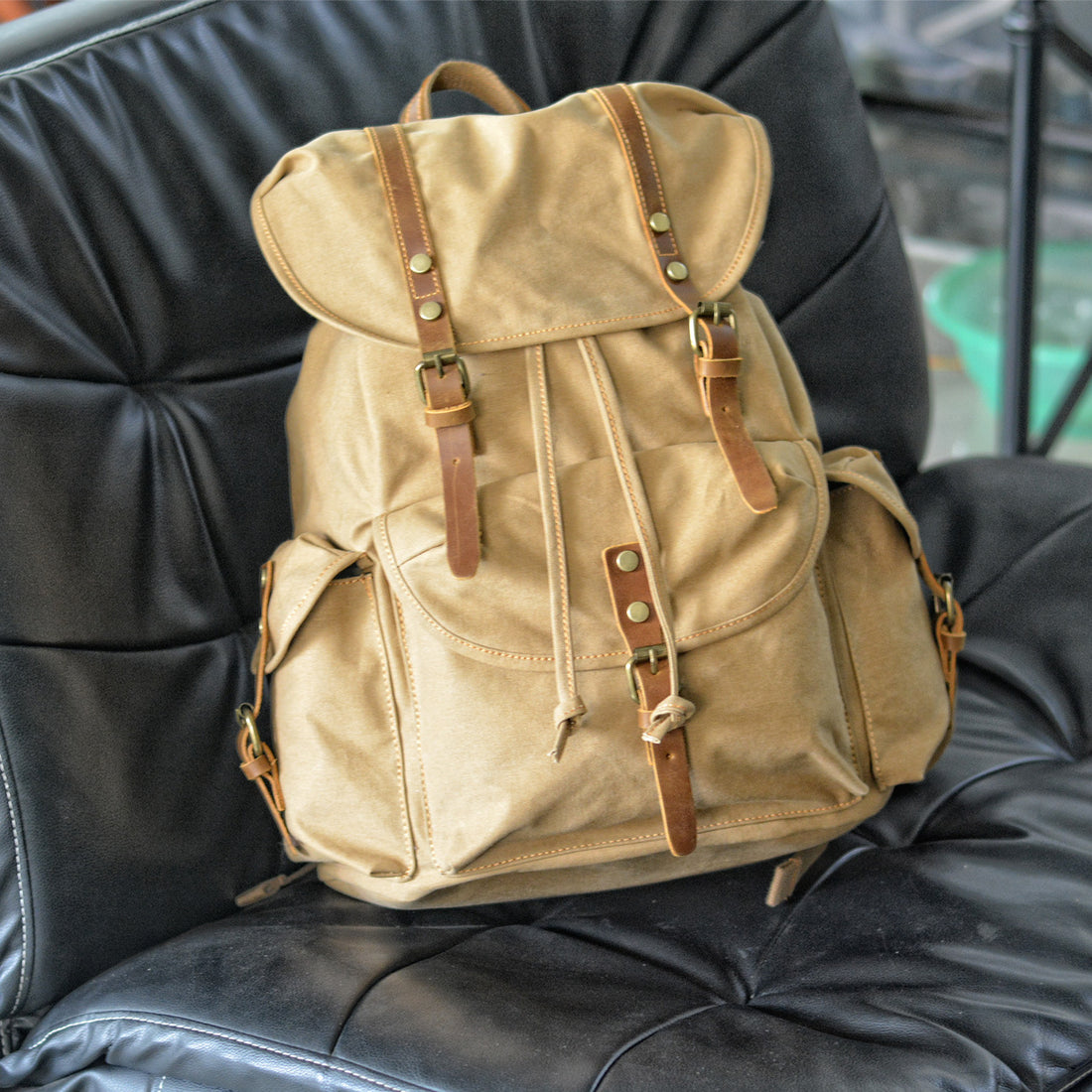 a army green canvas backpack is put in a black sofa-woosir