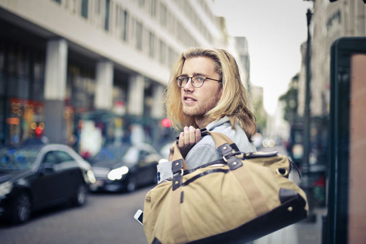 Man holding a canvas duffle bag on a city street