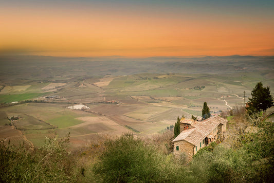 Serene view of Tuscany rolling hills and rustic house during vibrant sunset in Italy