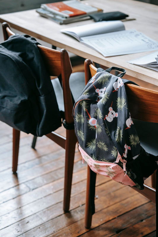 School desks with stationery and student backpacks in a classroom