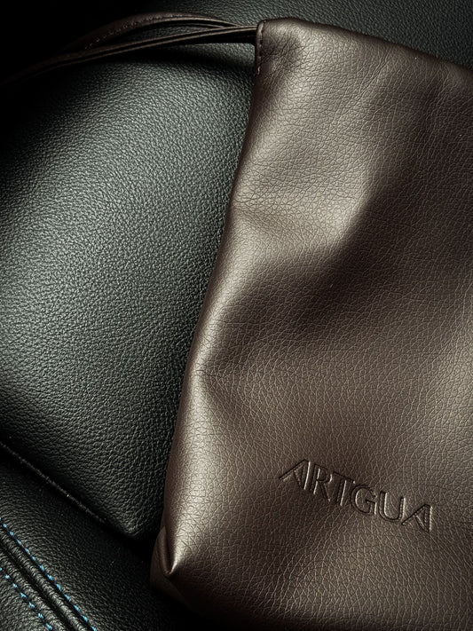 Close-up of a brown vintage leather bag on a dark leather surface
