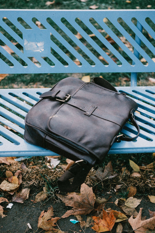 Vintage leather messenger bag resting on a park bench in autumn